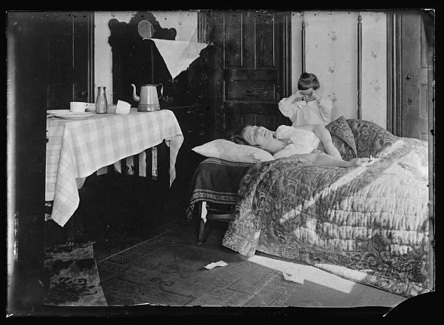 US woman sick with influenza in her home in 1918 with young child crying nearby